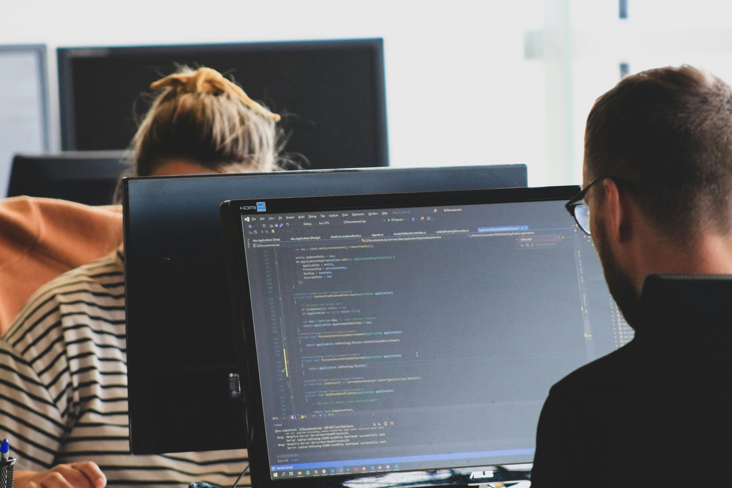 Man and women coding on large computer